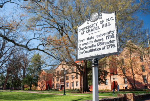 UNC Chapel HIll campus and sign claiming “the first state university to open its doors.”